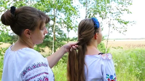 Mom in the meadow makes braid eldest daughter Stock Footage 96194436