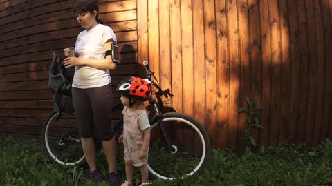 Mom opens a jar with smoothies for her daughter standing next to a wooden fence Stock Footage 78674271
