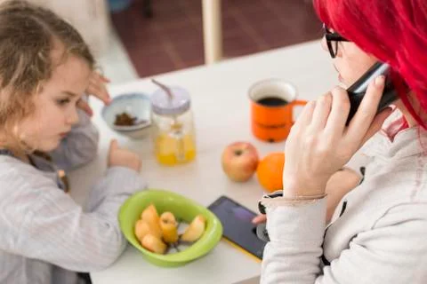 Mom on the Phone by Table of Snacks While Child Looks Bored Stock Photos