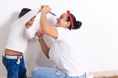 Mom playing her son while painting Stock Photos