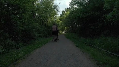 Mom pushing a stroller down a walking path at park Stock Footage 125288532