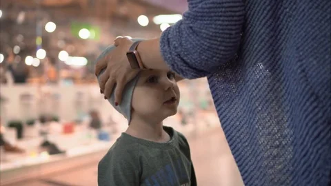Mom puts on a small son's hat in the store and talks to him Stock Footage 82078475