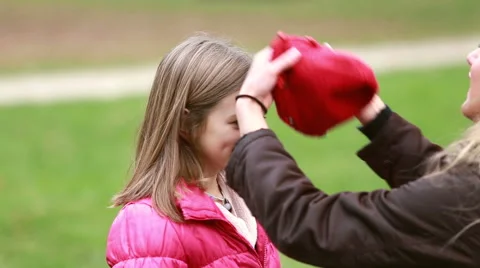 Mom putting cap on daughter's head and kissing her in forehead Stock Footage 59554612