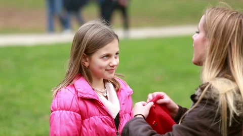 Mom putting cap on daughter's head and kissing her in forehead Stock Footage 59554642