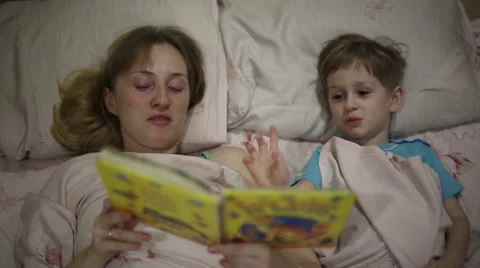 Mom reading the book to son bedtime Stock Footage 60404148
