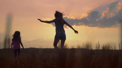 Mom runs with the daughter on the sunset, throws up and spins the happy child Stock Footage 80343043