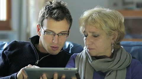 Mom, son and tablet computer sitting together on couch at home 動画素材 34275922