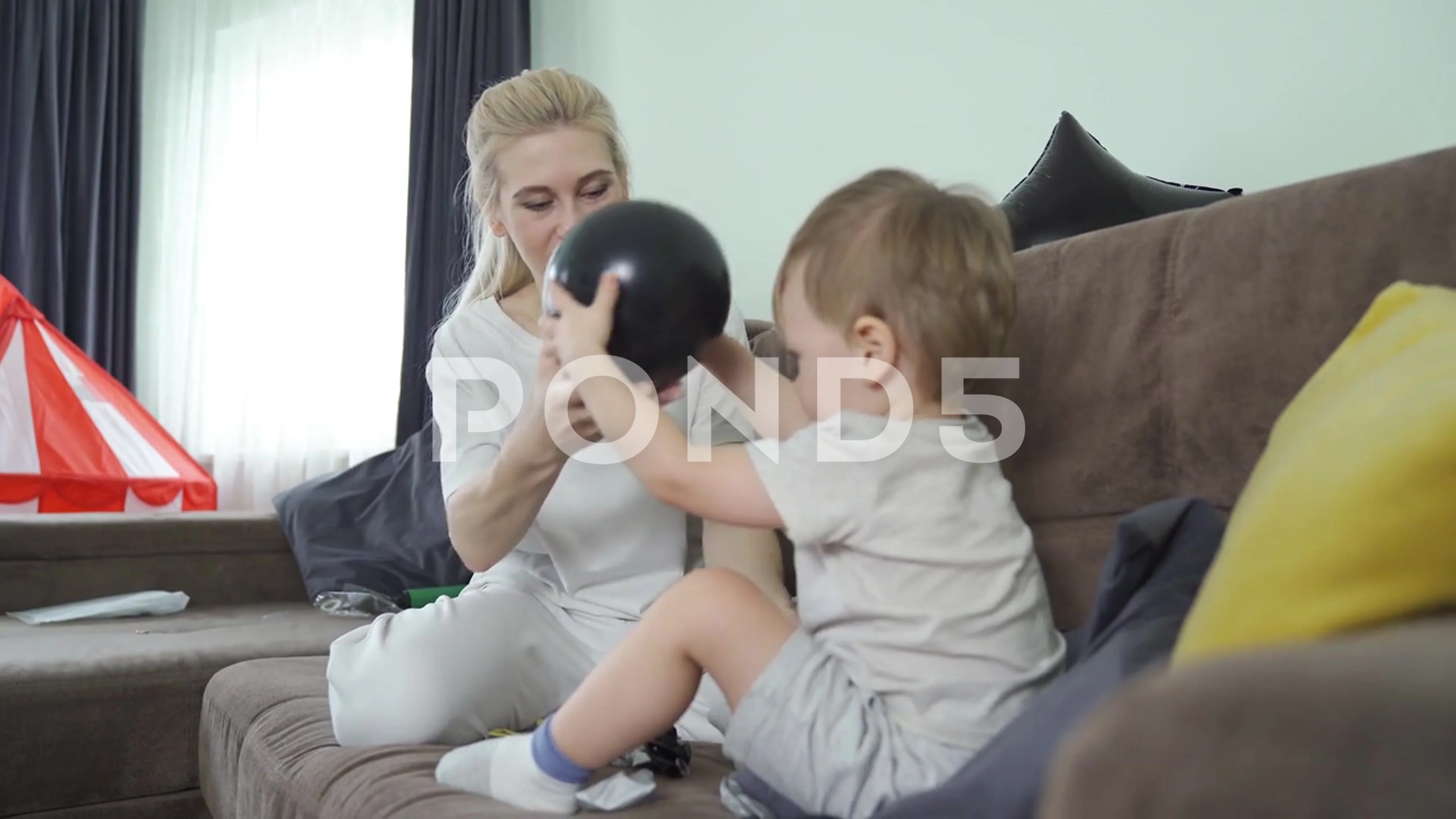 Mom With Son On Sofa Playing With Balloons