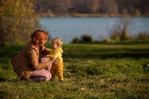 .Mom squatted down next to her son against the background of an autumn forest Stock Photos