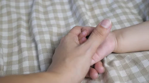 Mom strokes the baby's hand while he sleeps. Stock Footage 201188698