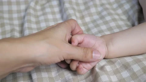 Mom strokes the baby's hand while he sleeps. Maternal care of the baby. Mom puts Video stock 201400938
