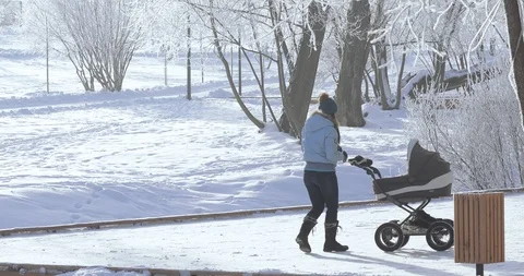 Mom with a stroller in the winter park Stock Footage 100057745