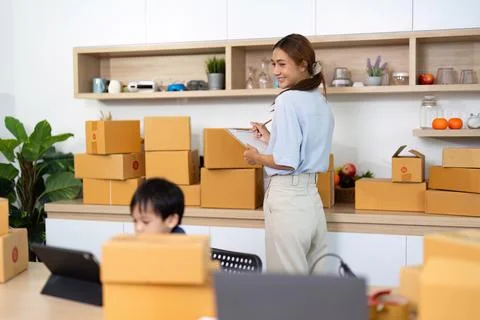 Mom taking notes while son engages with technology Stock Photos