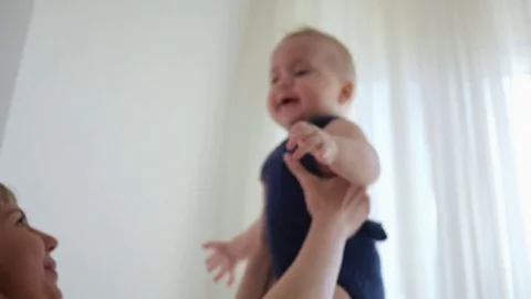 Mom throws his young son up standing at the window Stock Footage