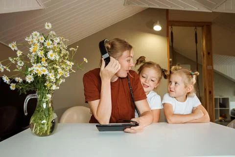Mom is trying to work or comminicate online, her two daughters interrupting her Stock Photos
