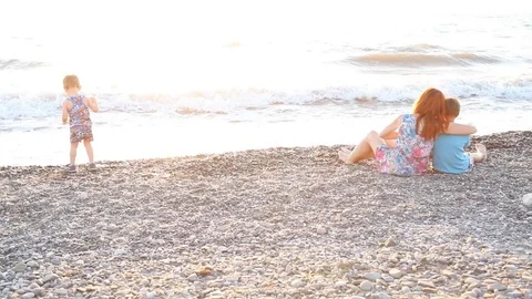 Mom with two boys sitting on a beach with sons sea Stock Footage