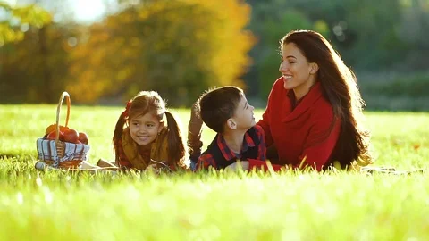 Mom with two children lying on the grass happy under the tree Stock Footage 101081106