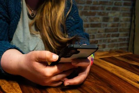 Mom using smartphone in cozy setting, relaxed atmosphere with wooden table .. Stock Photos