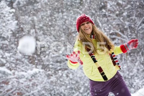 Moment of play: young woman flinging the snowball Stock Photos