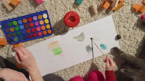 Moms and childs hands in process of painting their family pet,gray cat,top view Stock Footage 234980970