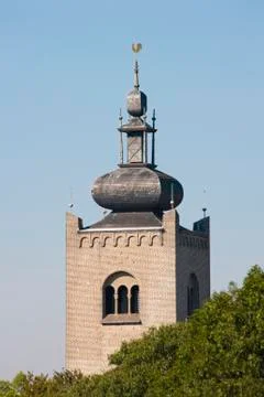 Monastery tower behind tree tops Stock Photos