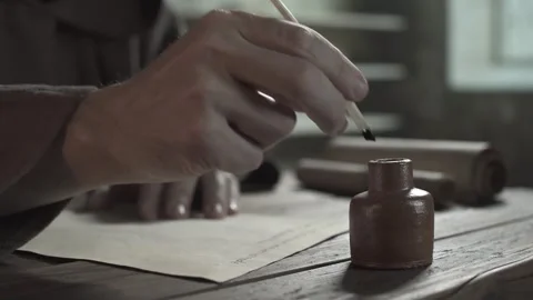 Monastic scribe in a brown robe writing with a large quill pen on a page Stock Footage 339231782