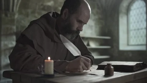 Monastic scribe with a long white quill pen copying from an open old book Stock Footage 340322626