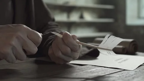 Monastic scribe sharpening a feather pen and testing the quill tip with a finger Stock Footage 338991750