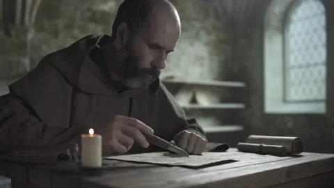 Monastic scribe studying a manuscript while following text with a penknife Stock Footage 337929720