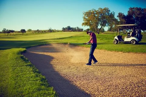 Mondays are sand traps in the fairway of life. a golfer chipping his ball out of Stock Photos