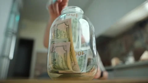 Money being counted and stored in a glass jar during a financial planning Stock Footage 300773654