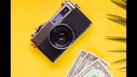 Money camera compass clock concept travel on yellow background with palm leav Stock Footage 128897059