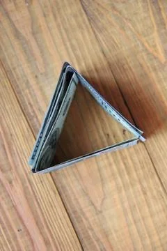 Money in cash in triangular shape standing on wooden surface. Hundred dollars Stock Photos