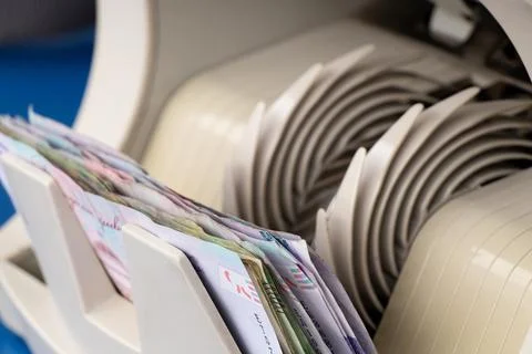 Money counting machine with a stack of Ukrainian hryvnias on a blue table, th Stock Photos
