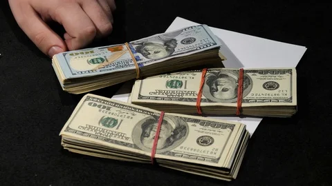 Money is falling on the table with a written amount on paper near the hand. Stock Footage 129786674