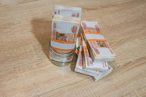 Money in a flat jar on the table Stock Photos