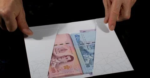 Money is placed inside an envelope with hands showing cash from different curren Stock Photos