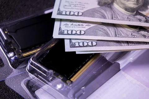 Money placed on top of computer components with cash spread across technology in Stock Photos