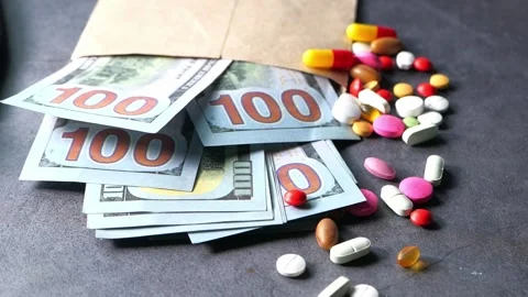 Money scattered with assorted pills and capsules near a brown envelope on d.. Stock Footage 332626332