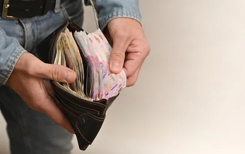 Money stack taken from open wallet in hands of man. Stock-Fotos