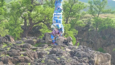 Mongolia ovoo shrine stands on open steppe, sacred stone cairn - Khata Scarf Stock Footage 339816636