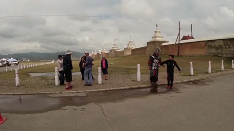 Mongolian warrior in armor with tourists around the ancient walls of a Buddhist  Stock Footage 54647448