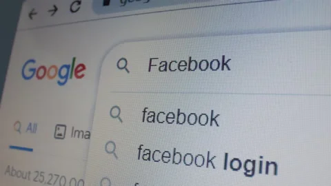 Monitor screen with a google page and typing the search term Facebook Stock Footage 235159553