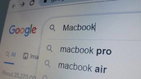 Monitor screen with a google page and typing the search term Macbook. Stock Footage 235160639