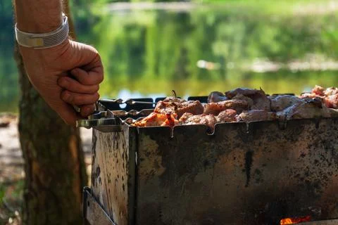 Monitoring barbecue grill while meat cooks over charcoal Fotos de archivo
