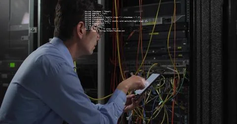 Monitoring engineer in blue shirt tapping tablet at rack in server room, cables Stock Photos