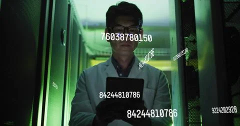 Monitoring Korean engineer in lab coat holding tablet in narrow server rack Stock Photos