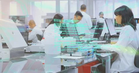 Monitoring lab-coated tech at right bench in lab typing and handling sample Stock Photos