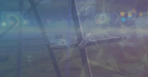 Monitoring security camera on pole at barbed wire fence at dusk, with digital 库存照片