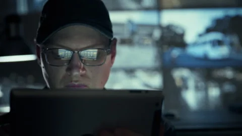 Monitoring security feeds an employee in glasses and special attire analyzes Stock Footage 334545948